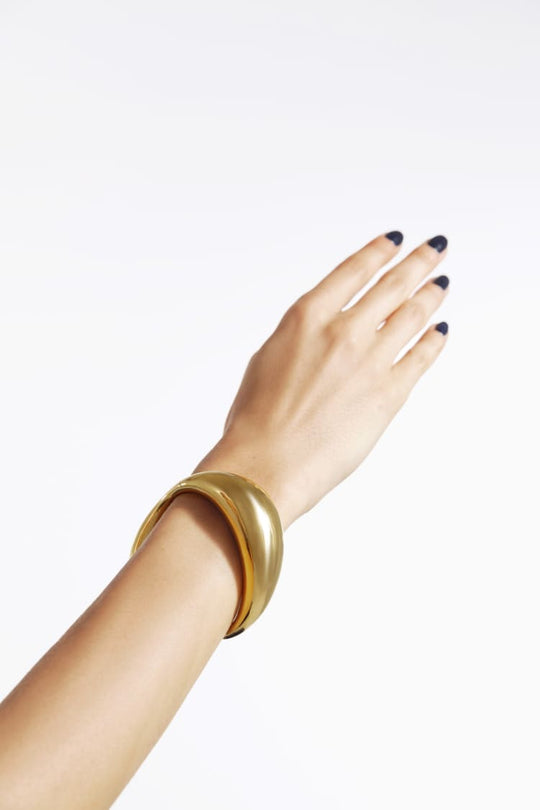 pulsera redonda asimétrica y gruesa con cierre en oro